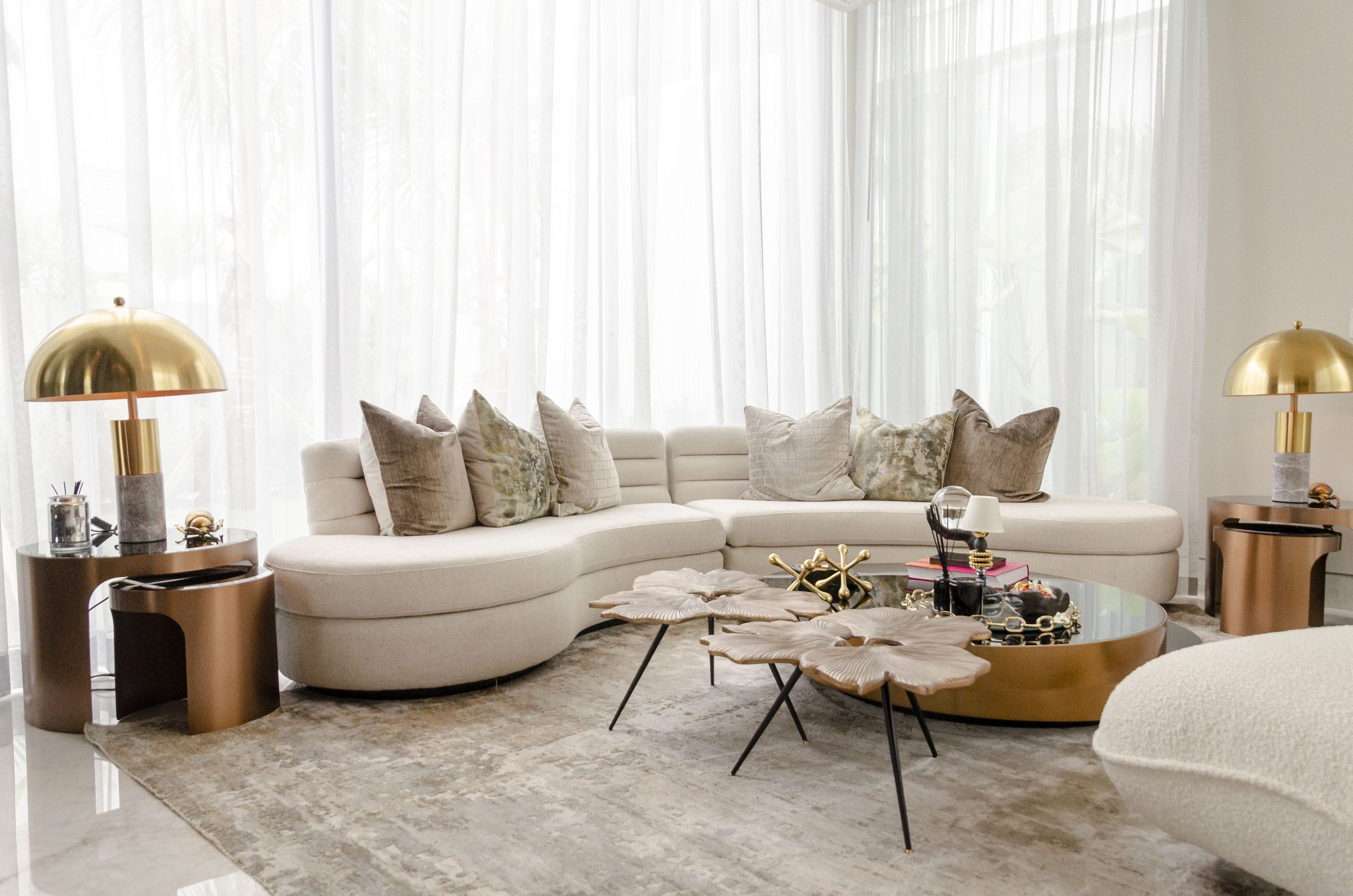 Sala luminosa con sofá curvo en bouclé y lámparas de latón — diseño de Cindy Kronfle