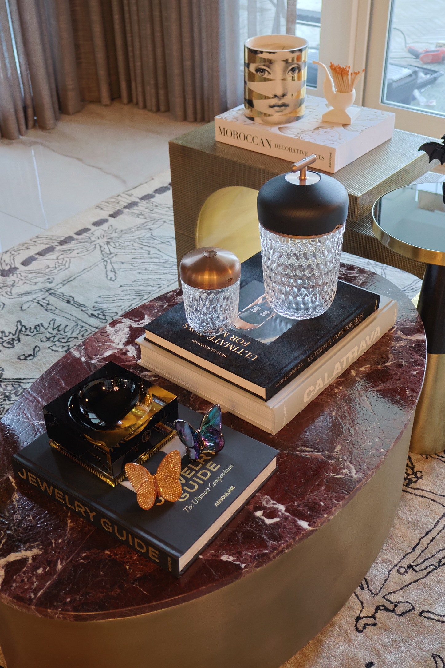 Detalle de mesa — mármol rosso, libros Assouline, mariposas
